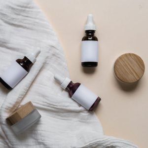 Elegant glass skincare bottles with labels on a textured fabric, perfect for cosmetic branding and product display.